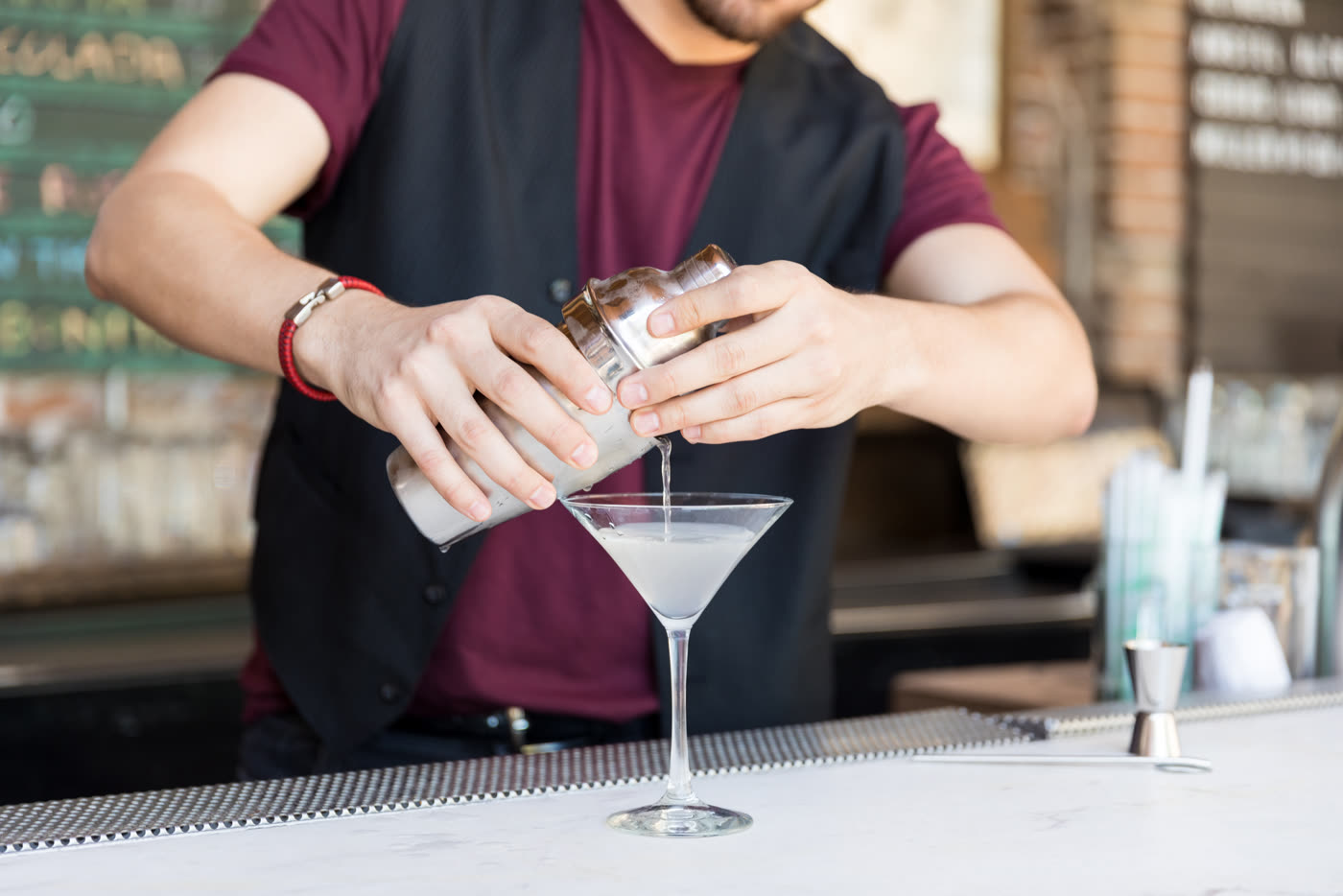 A bartender pouring a cocktail